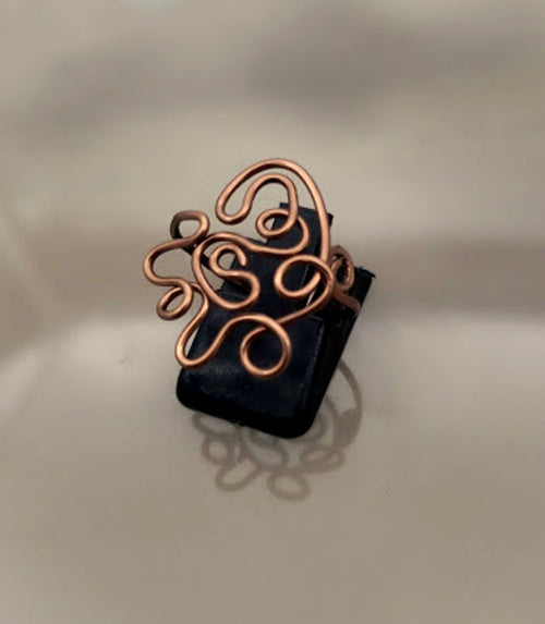 Handcrafted antiqued copper expression ring showing sculptural wire design on black base
