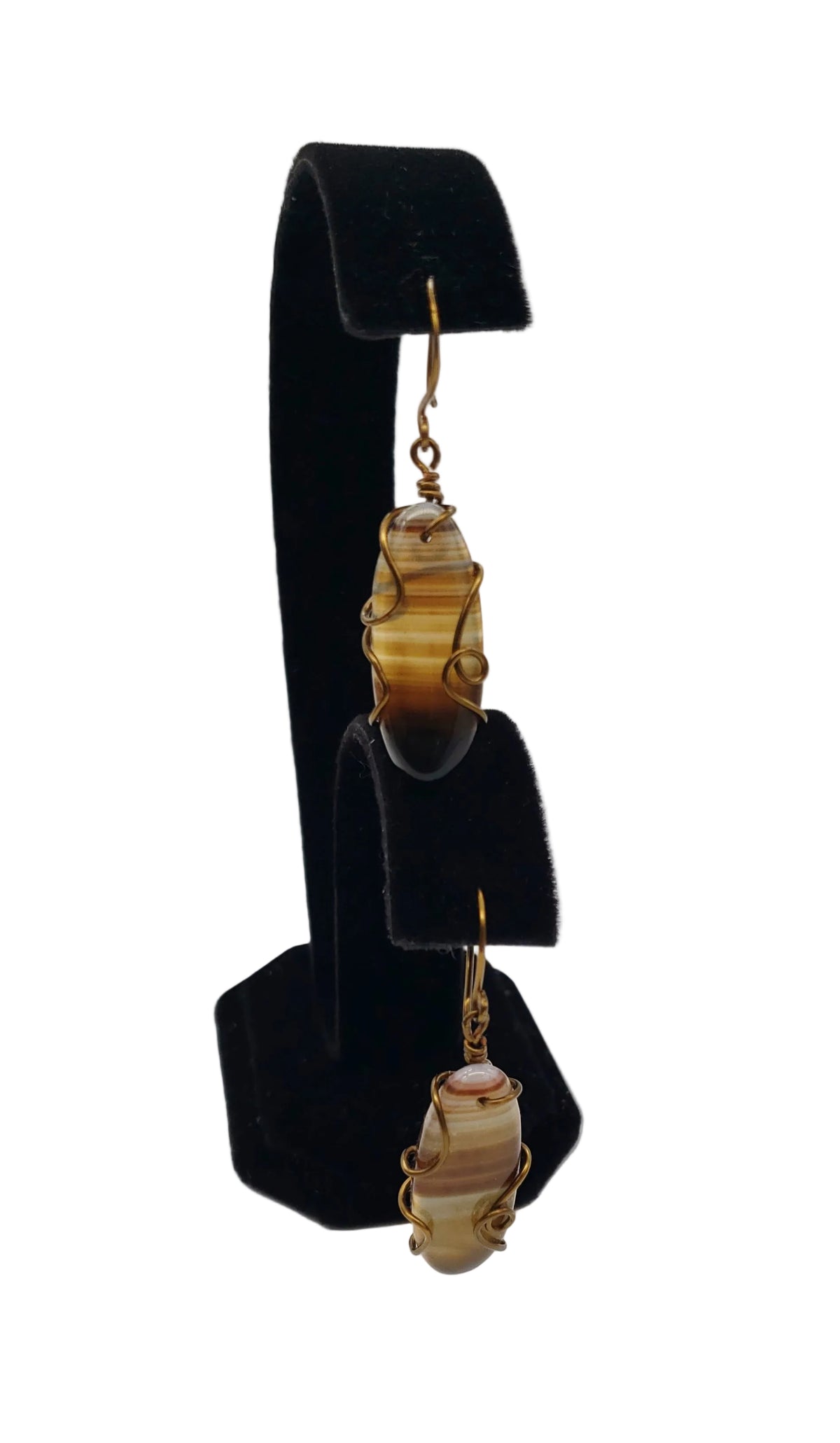 Pair of striped agate wire-wrapped earrings displayed on a black jewelry stand, showing their elongated natural stone design